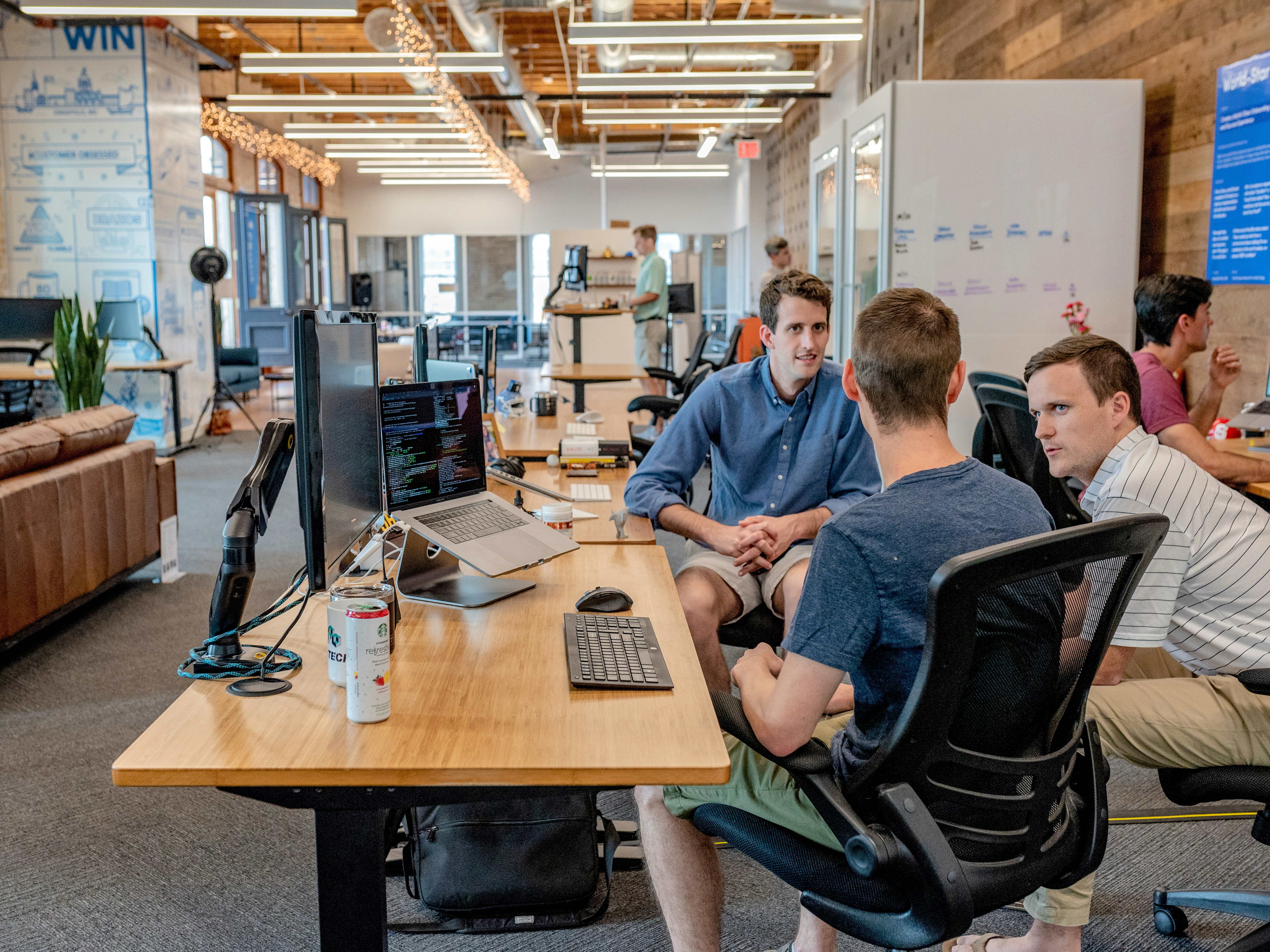 A small team working together at a desk of monitors and laptops