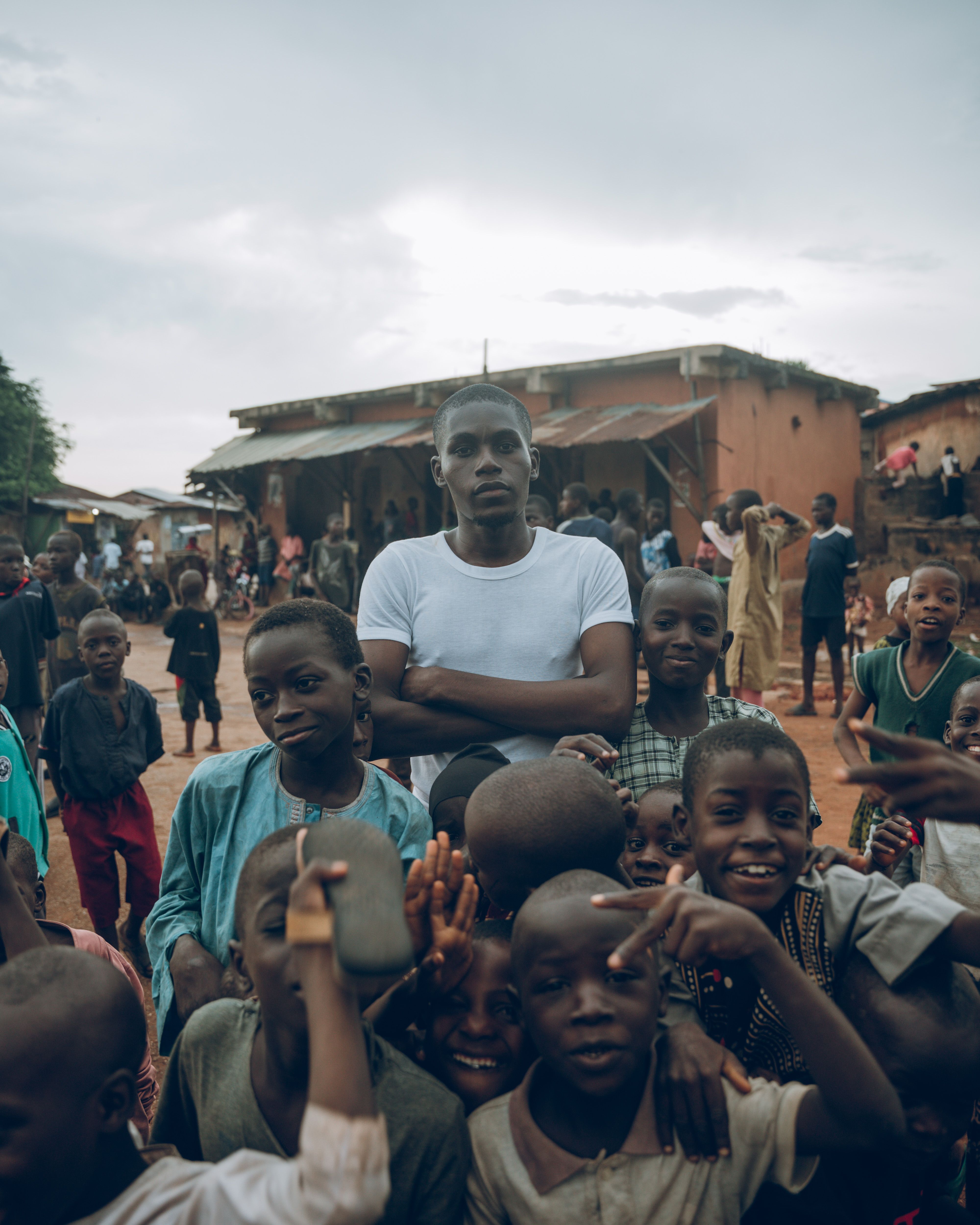 A young community leader standing with a group of children in a village street